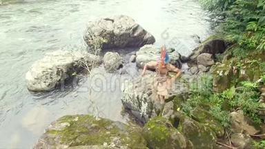 土著战士攀登河流边缘的岩石
